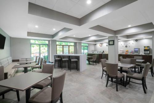 a restaurant with tables and chairs and a bar at Wingate by Wyndham Charlotte Airport in Charlotte
