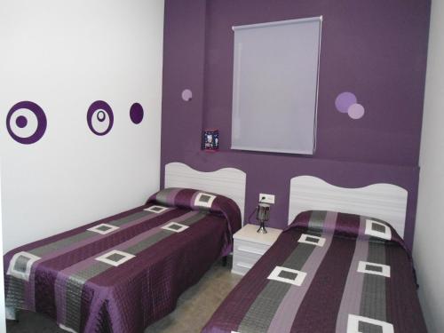 two beds in a room with purple and white walls at casa Mariona in Riumar
