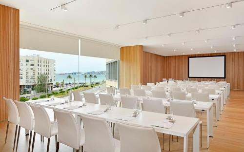 a conference room with white tables and chairs and a screen at Melia Palma Bay in Palma de Mallorca