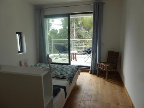 Cette chambre dispose d'un lit et d'une porte coulissante en verre avec un balcon. dans l'établissement Villa Lucienne Bandol, Maison d'architecte, 5 étoiles, calanques, à Bandol