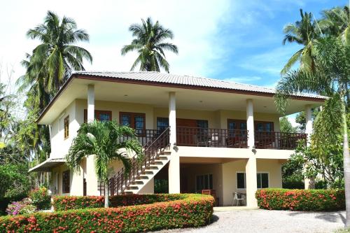 a house with a balcony and palm trees at Kate House Bangsaphan in Bang Saphan
