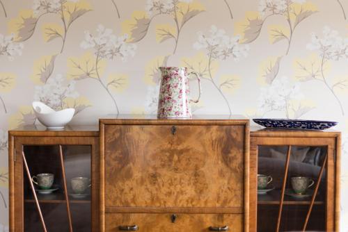 a dresser with a vase on top of it with a wallpaper at Deighton Lodge in York