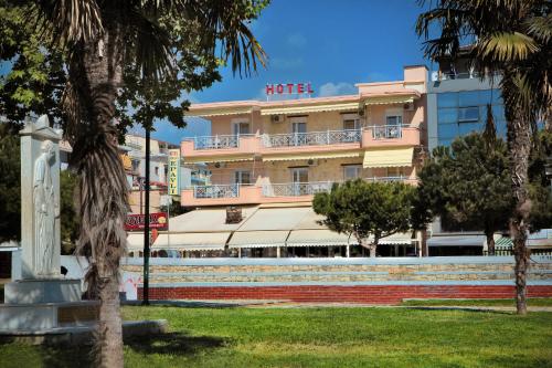 a hotel in front of a park with palm trees at Hotel Epavli in Nea Kallikrateia