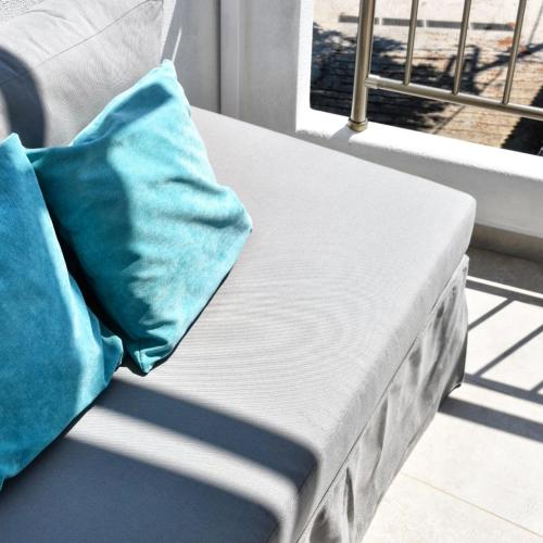a bed with a blue pillow sitting next to a window at Angelos Boutique Suites in Patitiri