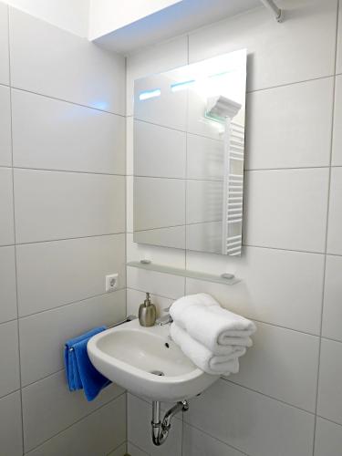 a white bathroom with a sink and a mirror at Apartment Möwe in Meersburg
