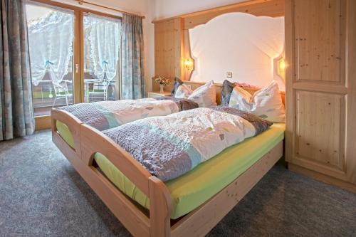 - une chambre avec un lit en bois et une grande fenêtre dans l'établissement Appartement Flora, à Saas-Almagell