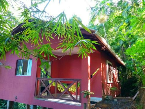 une maison rouge avec une porte rouge et des arbres dans l'établissement Casa da Floresta, à Parati