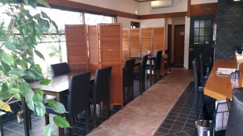 um restaurante com mesas e cadeiras pretas e uma sala em Guest House Kuranomachi ゲストハウス蔵の街 em Tochigi