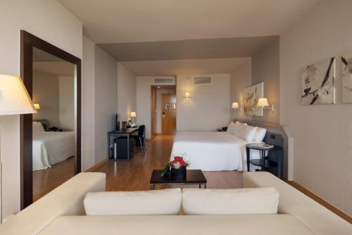 a hotel room with two beds and a couch at Ciutat de Granollers in Granollers