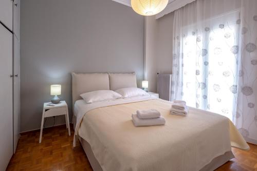 een slaapkamer met een wit bed en 2 handdoeken bij Artemis - Athens Deluxe City Center Apartment in Athene