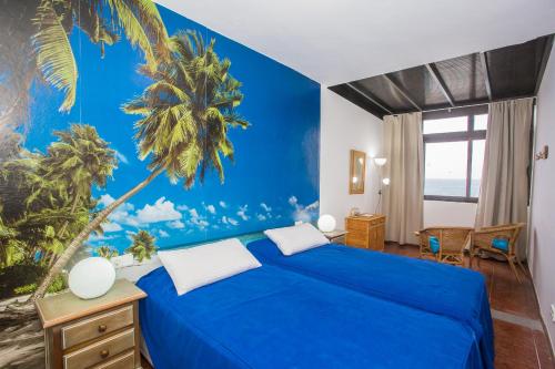 a bedroom with a blue bed with a palm tree mural at Apartamento Vista Mar in Playa Blanca