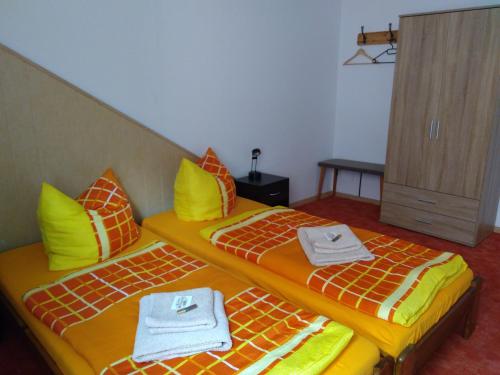 2 camas en una habitación con almohadas amarillas y naranjas en Ferienwohnung Weiß, en Aue