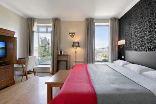 Schlafzimmer mit einem großen Bett, einem Schreibtisch und einem Fenster in der Unterkunft Hotel Bonaparte in Montreal