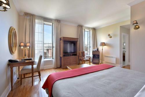a bedroom with a bed and a desk and a television at Hotel Bonaparte in Montréal