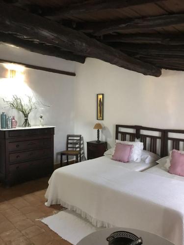 a bedroom with a large white bed with pink pillows at Casa Rural Donatila in Villasbuenas de Gata