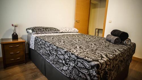 una camera da letto con un letto con un piumone bianco e nero di Apartments Madrid Eliptica a Madrid