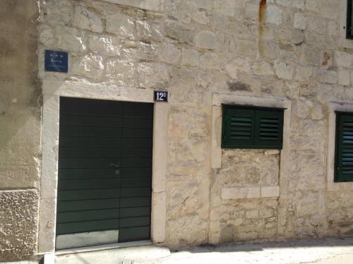 un edificio de piedra con 2 puertas de garaje y 2 ventanas en Cosy accommodation in the center of Split, en Split