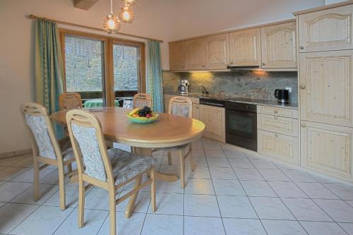 a kitchen with a wooden table with chairs and a bowl of fruit at Appartement Flora in Saas-Almagell