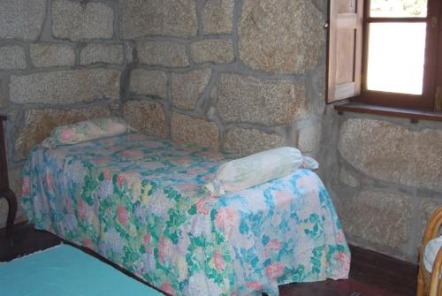 a bed in a room with a stone wall at Agro-Turismo Quinta do Pendao in Santa Cruz da Trapa