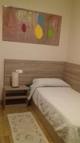 1 dormitorio con cama, mesita de noche y pintura en Residencia Diego Martinez, en Palencia