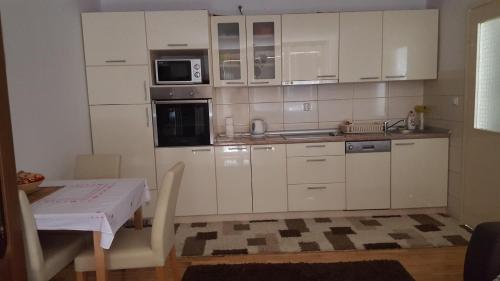 a kitchen with white cabinets and a table and a microwave at Apartment Zenica in Zenica