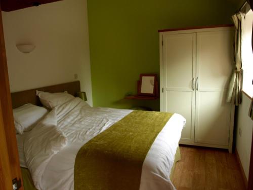 1 dormitorio con cama blanca y paredes verdes en The Courtyard at Lodge Farm, en Norwich