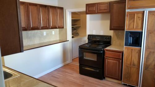 - une cuisine avec des placards en bois et une cuisinière noire dans l'établissement 500/502 W 23rd St, à Cheyenne