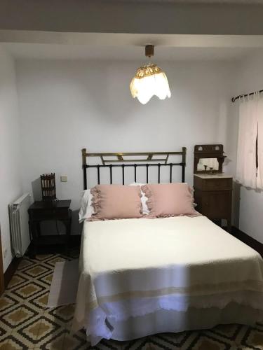 a bedroom with a bed with pink pillows and a chandelier at Casa Rural Donatila in Villasbuenas de Gata