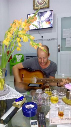 a man playing a guitar on a table at NGỌC QUÝ Mini House in Quy Nhon