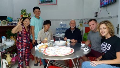 a group of people sitting around a table with a pizza at NGỌC QUÝ Mini House in Quy Nhon