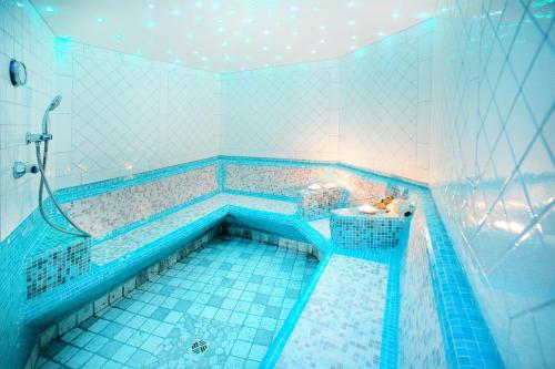 y baño con bañera y azulejos azules. en Hotel Rierhof, en Chiusa