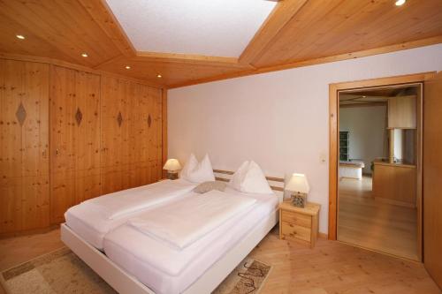 ブルック・アン・デア・グロースグロックナーシュトラーセにあるWohnung Zur Postの木製の壁の客室で、白い大型ベッド1台が備わります。