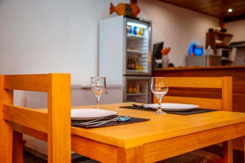 a wooden table with two plates and glasses on it at Albergaria Porcelana in São Tomé