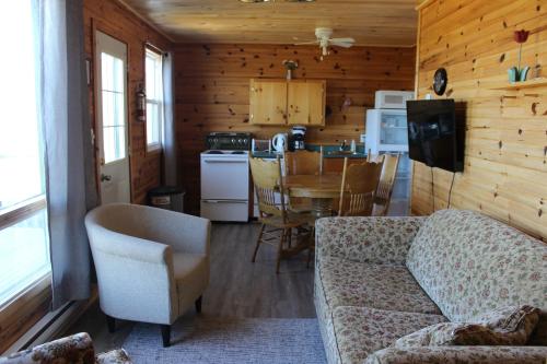 a living room with a couch and a table and a kitchen at Chalets Grand Pre Cottages in North Rustico