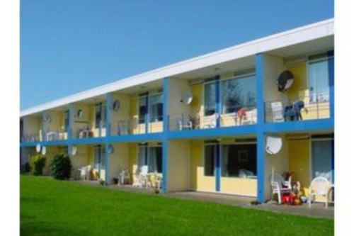 a blue and yellow apartment building with a green lawn at Vakantiehuisje Martina 24 in Vlissingen