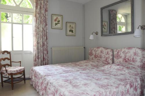 1 dormitorio con cama, silla y espejo en Le clos des Acanthes, en Vouvray