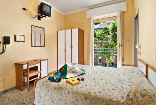 a bedroom with a bed and a table and a window at Hotel Grappoli in Rimini