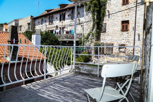 a white chair sitting on a balcony next to a building at Kolbe Hvar Piazza Apartment in Hvar