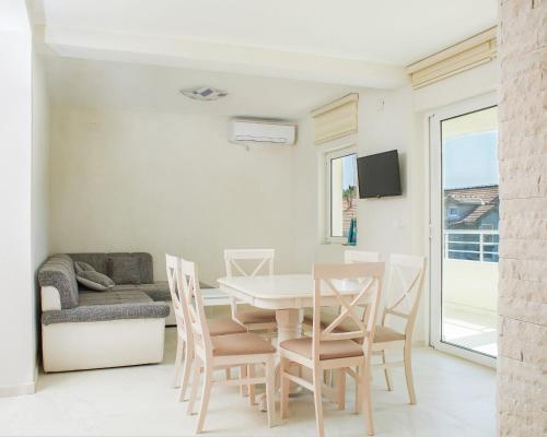 a dining room with a table and chairs and a couch at Apartmani Tripović in Tivat