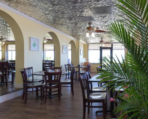 un comedor con mesas, sillas y ventanas en Sand Dunes Resort & Suites en Myrtle Beach