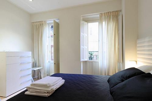 a bedroom with a bed and a dresser and windows at Flatsforyou Sorolla House in Valencia