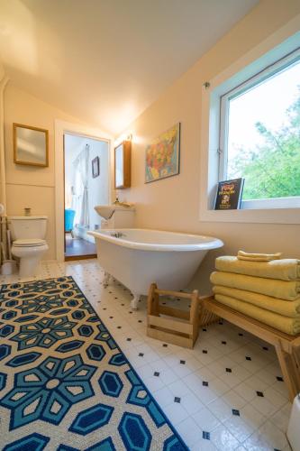 a bathroom with a tub and a toilet and a window at People’s House in Port Townsend