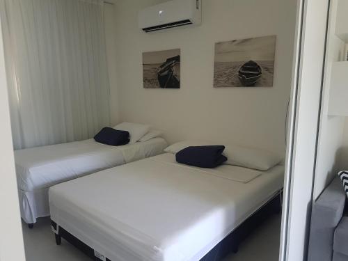 two twin beds in a room with two pictures on the wall at Solar Água - Apto. 114 in Pipa