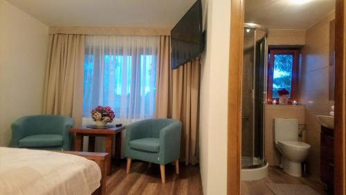 ザコパネにあるPokoje w CENTRUM "CICHA"のベッド1台、椅子2脚、バスルームが備わる客室です。