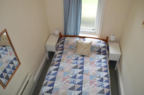 a small bedroom with a bed with a quilt on it at Hargate Hall Self Catering in Buxton