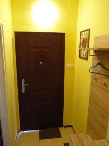 a brown door in a room with a yellow wall at Eper Apartman in Debrecen