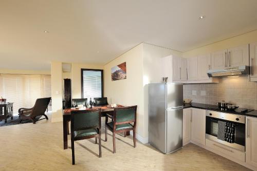a kitchen with a table and a stainless steel refrigerator at Beach Hotel Swakopmund in Swakopmund