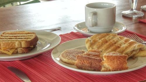 ein Tisch mit zwei Tellern Essen und einer Tasse Kaffee in der Unterkunft Pousada Nascer do Sol in Fernando de Noronha