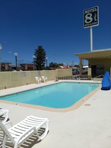 a swimming pool with lounge chairs and a speed limit sign at Motel 8 Willcox in Willcox