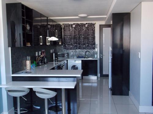 a kitchen with a counter and stools in it at Unit 46 @ 77 on Independence in Windhoek
